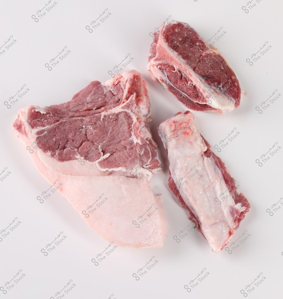 An image showing slices of raw meat placed on a white surface. The image includes a relatively large piece of meat and a smaller piece beside it. The meat appears red with sections of white fat.