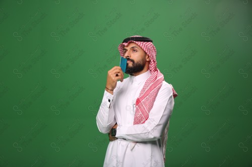 بورتريه رجل سعودي على خلفية خضراء محتار يحمل بطاقة الصرافة