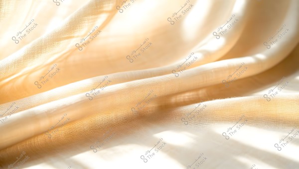 An image showing light-colored fabric with warm lighting. The fabric appears soft and naturally folded, giving a sense of warmth and comfort. Light filters through the fabric, leaving soft shadows.