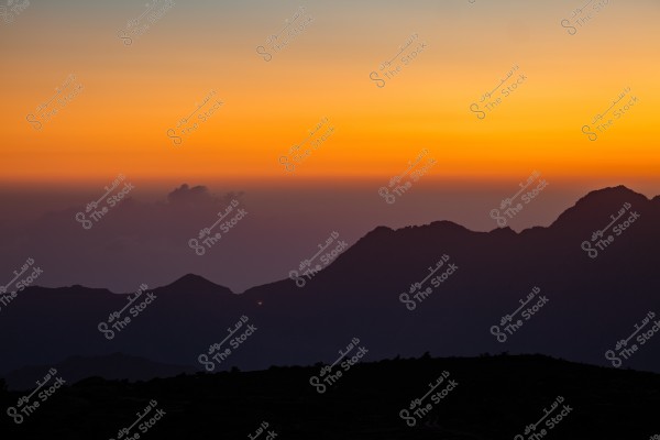 An image depicting a mountainous scene at sunset. The sky is a gradient of vibrant orange and purple with dark clouds on the horizon. The silhouette of the mountains appears at the top of the image, adding a sense of calm and majesty.