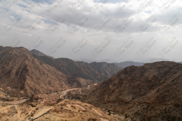 لقطة لجبال محافظة عسير تحيط بها مدرجات زراعية وتظهر السماء شبه غائمة نهارًا، اشجار وغابات، الطبيعة في السعودية