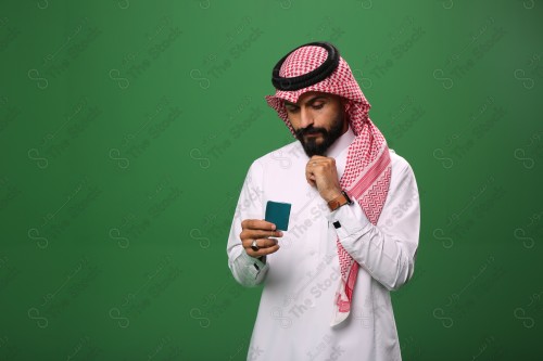 بورتريه رجل سعودي على خلفية خضراء محتار يحمل بطاقة الصرافة.