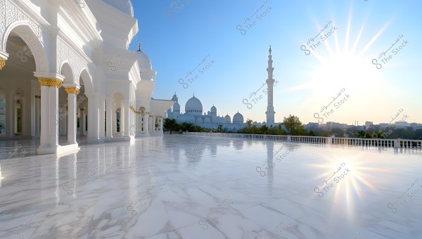 The image depicts a large mosque with distinctive Islamic architecture featuring white domes and tall minarets. The floor is made of polished marble, reflecting the bright sunlight illuminating the scene. There are arches with golden details on the edges, with a landscape of trees in the background and buildings on the distant horizon.