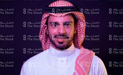 بورتريه رجل سعودي أمام خلفية سوداء يرتدي الثوب ويبتسم. صورة شخصية لرجل سعودي مبتسم