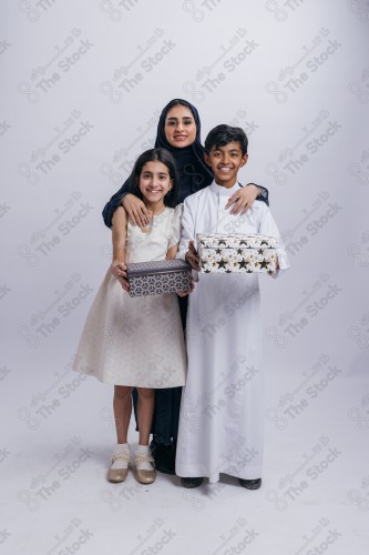 Portrait of a Saudi family on a white background making gestures with their hands while smiling, souvenir photos, documenting a happy moment, Eid gifts, Eidiyat,