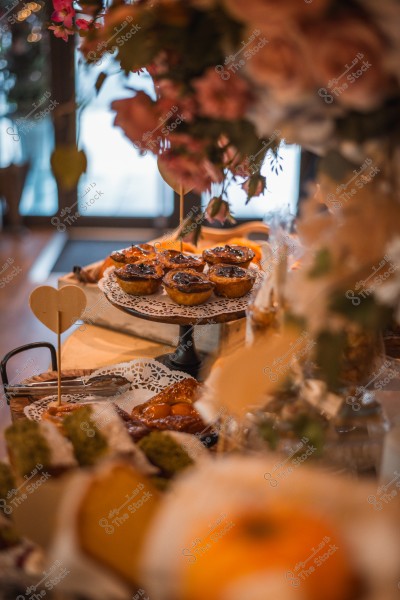 A table decorated with flowers featuring a variety of tarts and pastries arranged beautifully.