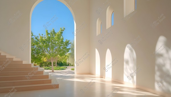 An interior view showing a wide staircase on the left leading to a large arch opening to a sunlit outdoor garden. Light reflections are cast on the light honey-colored interior walls with smaller arched windows, and a green tree is visible in the garden outside under a clear blue sky.