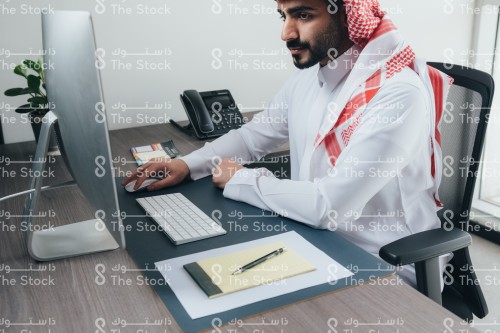 موظف سعودي يرتدي الثوب ويعمل في مكتبه