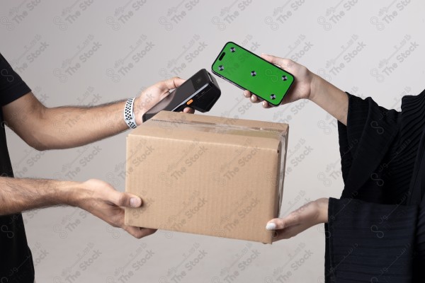 Portrait of a Saudi woman holding a card and making automatic payments, with a cardboard next to her on a white background