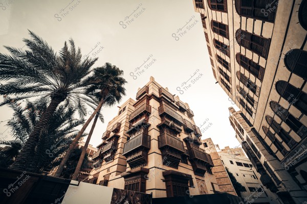Here’s the translation of your text into English:\r\n\r\n\"A historical image of Jeddah showing a traditional multi-story building at the corner, clearly displaying its unique architectural design with stone and wooden balconies. The surrounding buildings appear slightly worn, giving the area a historical character. The streets are cobblestone, with a wooden chair in front of the central building, and a palm tree visible in the background.\"\r\n\r\nIf you want, I can also make a slightly more **natural, descriptive English version** that reads like a guidebook or historical caption. Do you want me to do that?\r\n