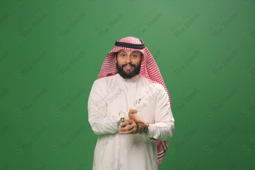 بورتريه رجل سعودي يرتدي الزي السعودي التقليدي يحمل زجاجة دهن عود ويتطيب