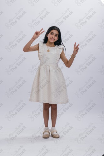 Portrait of a Saudi girl on a white background making gestures with her hands while smiling, souvenir photos, documenting a happy moment, Eid candy, Eid gifts, Eidiyat