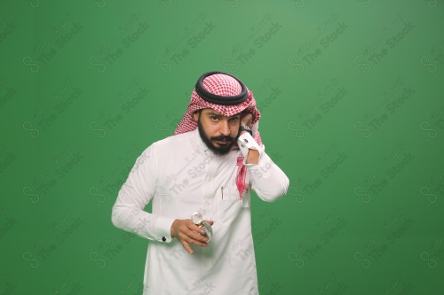 بورتريه رجل سعودي يرتدي الزي السعودي التقليدي يحمل زجاجة دهن عود ويتطيب