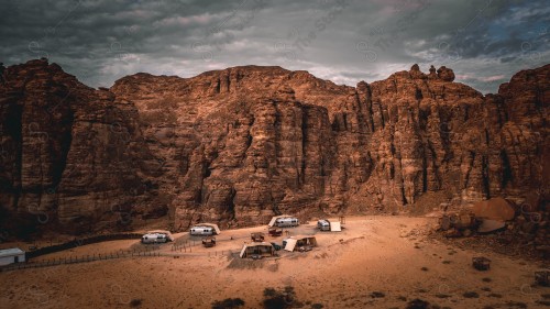 Side shot of a group of tents in the middle of the rocky mountains and the sky looks cloudy in the sky, camping and travel, road trips.