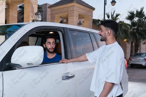 shot of two young Saudis chatting and having fun on the road, their features showing joy and happiness.