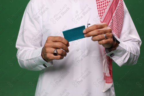 رجل سعودي على خلفية خضراء يحمل ببطاقة الصرافة مستعد للتسوق