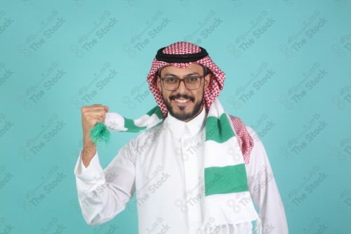 شاب سعودي يرتدي الزي السعودية ممسك شال بيده يقوم بتعابير وجه و يدين تدل على السعادة والحماس ، كأس العالم ، المنتخب السعودي.