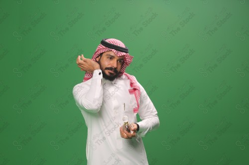 بورتريه رجل سعودي يرتدي الزي السعودي التقليدي يحمل زجاجة دهن عود ويتطيب