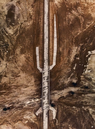 Overhead shot of a chain of rocky mountains of a paved road that cuts through the desert.