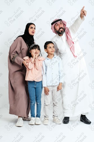 Portrait of a Saudi family looking towards a place, two children standing next to their parents pointing towards a goal, signs of happiness, a happy family atmosphere, the concept of a happy family, spending enjoyable family times