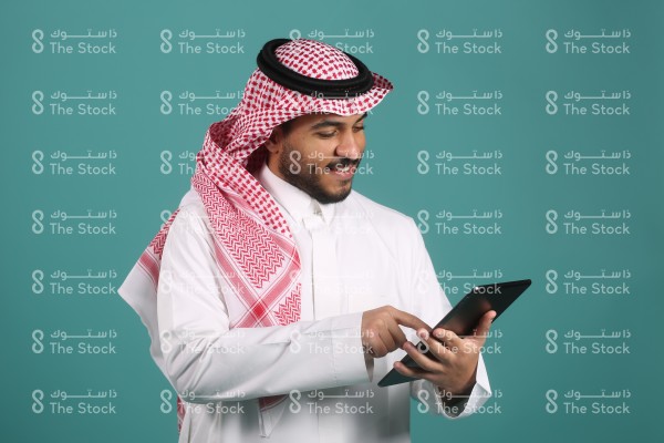 بورتريه رجل سعودي يرتدي الثوب مبتسم ، صورة لشاب سعودي يشاهد الجوال وتصفح الإنترنت ووسائل التواصل الاجتماعي