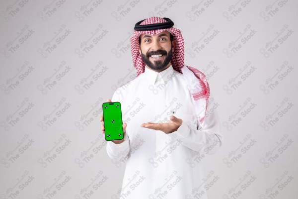 Portrait of a Saudi man holding a phone, pointing at the phone and making different expressions - green screen