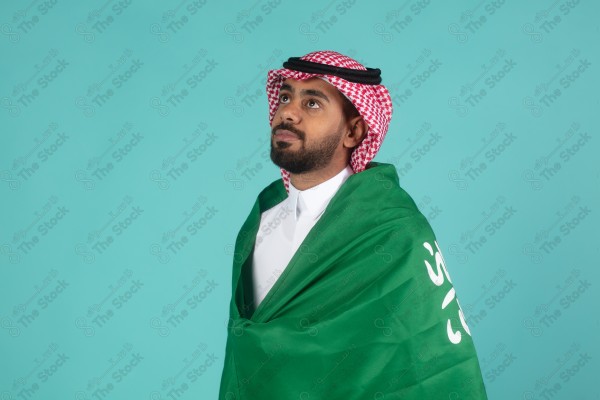 بورتريه رجل سعودي يحمل العلم السعودي على كتفه احتفالاً باليوم الوطني