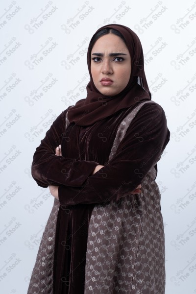 A young Saudi woman wearing an abaya and hijab, looking angry