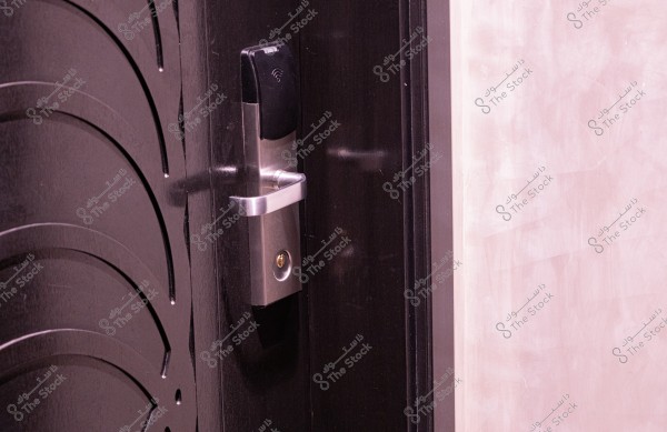 The image shows a dark wooden door with a modern stainless steel lock operated by smart card technology. The adjacent wall has a smooth, light-colored finish.
