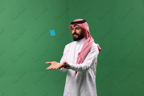 بورتريه رجل سعودي على خلفية خضراء متحمس يحمل بطاقة الصرافة مستعد للتسوق