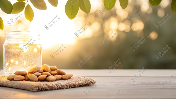 An image of a glass jar containing twinkling lights, placed on a wooden table. Next to the jar is a pile of almonds resting on a piece of burlap. In the background, green leaves are hanging from above, with a sunset creating a warm, glowing, and blurred backdrop.