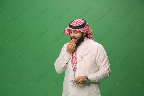 بورتريه رجل سعودي يرتدي الزي السعودي التقليدي يتناول الحلوى