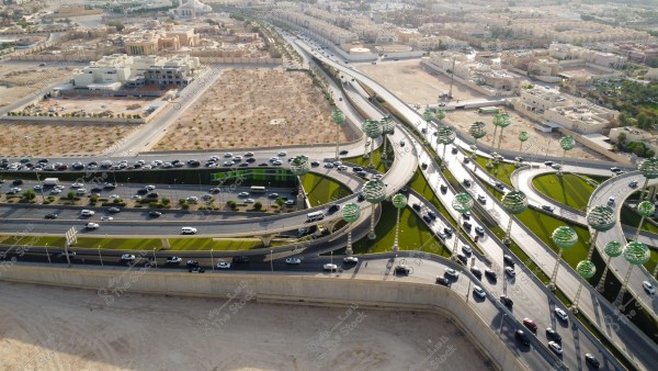 تصوير جوي لحركة سير السيارات على الطريق السريع في مدينة الرياض، الفن الهندسي المعماري للمجسمات الفنية على شكل أشجار خضراء، الطرق المتقاطعة في دوار عرقة بالمملكة العربية السعودية، البنية التحتية المتطورة