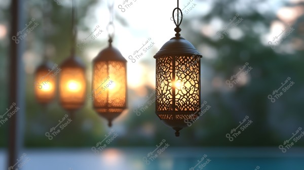 An image depicting a group of hanging metal lanterns with intricate geometric designs, emitting a warm, soft glow. The lanterns are set outdoors with a blurred green natural background.