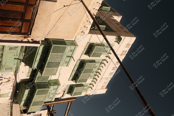 Facade of a traditional building adorned with light green painted wooden lattice windows under a blue sky.