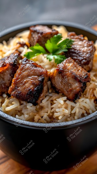An image of a dish featuring cooked white rice topped with crispy browned grilled meat pieces, garnished with fresh green parsley leaves. The dish is served in a black bowl placed on a wooden surface.