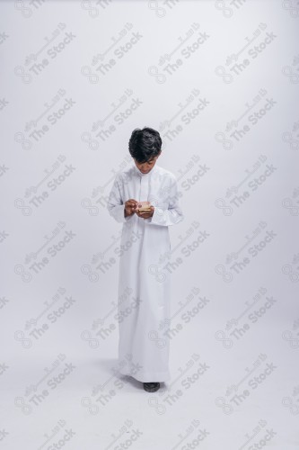 Portrait of a Saudi child on a white background making gestures with his hands while smiling, souvenir photos, ، documenting a happy moment, Eid candy, Eid gifts, Eidiyat, incense