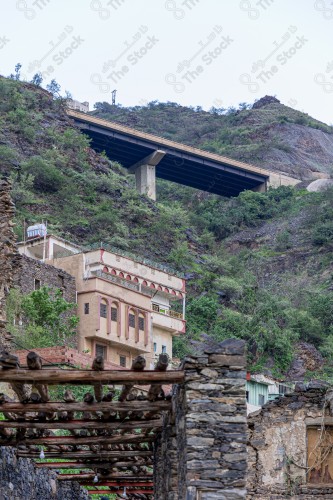 An ancient building built of stones in the middle of a group of windows surrounded by white paint while the sky looks cloudy during sunset, Rijal Almaa Heritage Village in the Asir region