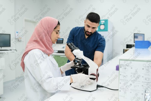 Saudi doctor in a hospital works in a laboratory, a medical team uses a microscope to examine a blood sample, and works in the field of health, providing medical consultations and medical health services.