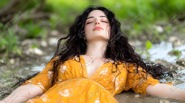 A woman lying in nature, wearing a floral yellow dress. She appears relaxed with her eyes closed. Her hair is long and wet, and the surrounding environment is green and calm.