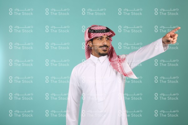 بورتريه رجل سعودي يرتدي الثوب الأبيض ويشير بيديه لاتجاه معين