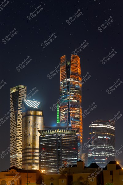 A nighttime image of the Riyadh city skyline in Saudi Arabia, featuring a collection of modern skyscrapers illuminated with colorful lights. The sky is filled with stars, adding a magical touch to the nighttime scene.