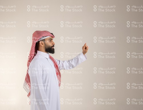 رجل سعودي يرتدي الزي السعودي التقليدي يشير بإصبعه السبابة للأعلى، رجل ينقر على أيقونة افتراضية