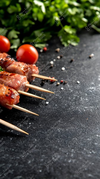 Grilled meat skewers laid angularly on a dark surface. Some cherry tomatoes and fresh parsley leaves appear in the background, along with scattered peppercorns.