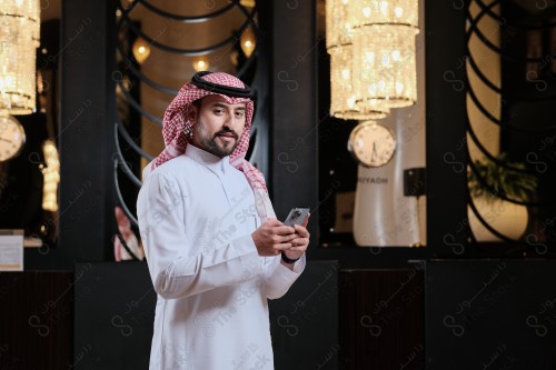 شاب سعودي في استقبال فندق ويقوم بتفاعلات متعددة ، ويظهر بيده حقيبة السفر