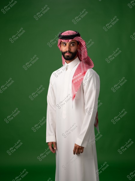 A portrait of a man wearing a traditional white thobe and a red ghutra with a black agal. He stands against a green background, gazing to the side. The attire suggests traditional clothing from Saudi Arabia.