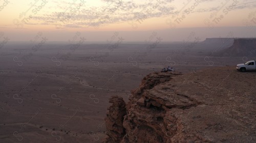 لقطة جوية لمجموعة سياح على جبل من جبال طويق المسمى بحافة العالم. سلسلة من الجبال الصخرية