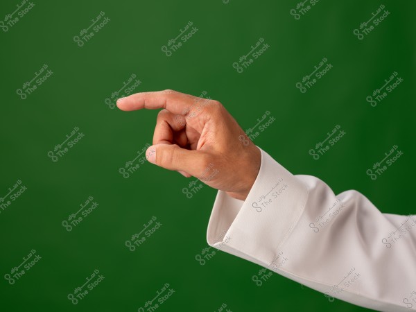 Image of a hand wearing a white shirt pointing with the index finger to the right, against a green background.