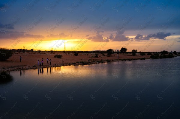 A snapshot of people standing at the waters of a valley in the city of Riyadh during sunset, nature in Saudi Arabia