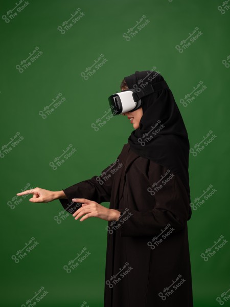 A woman wearing virtual reality glasses interacting with digital content using her hands on a green background.